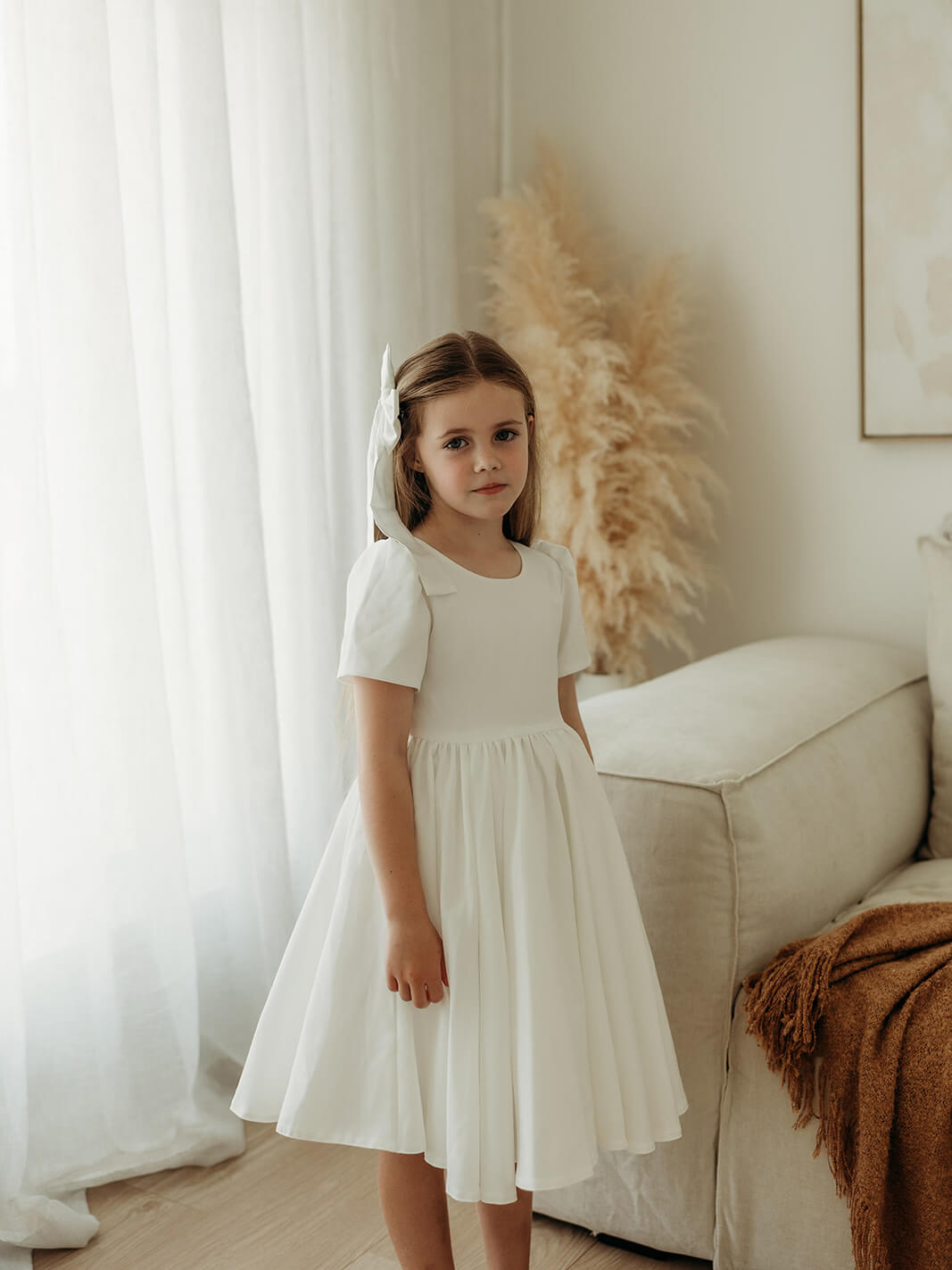 A little girl wears our Charlotte crepe flower girl dress and satin hair bow.