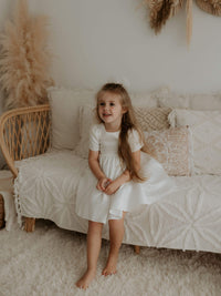 Our ivory satin flower girl dress, Charlotte, is worn by a young girl.