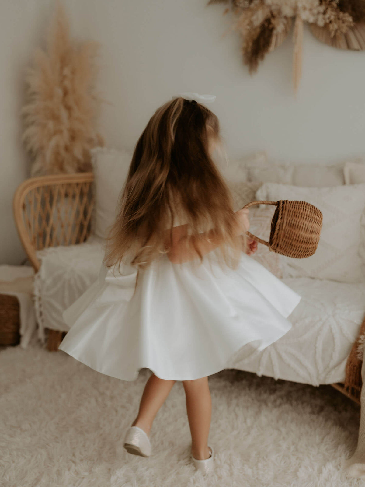 A young girl twirls in our satin flower girl dress, Charlotte.