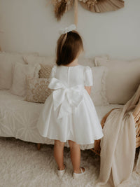 Charlotte flower girl dress in ivory, shown from the back, showing the large satin bow and zip closure.