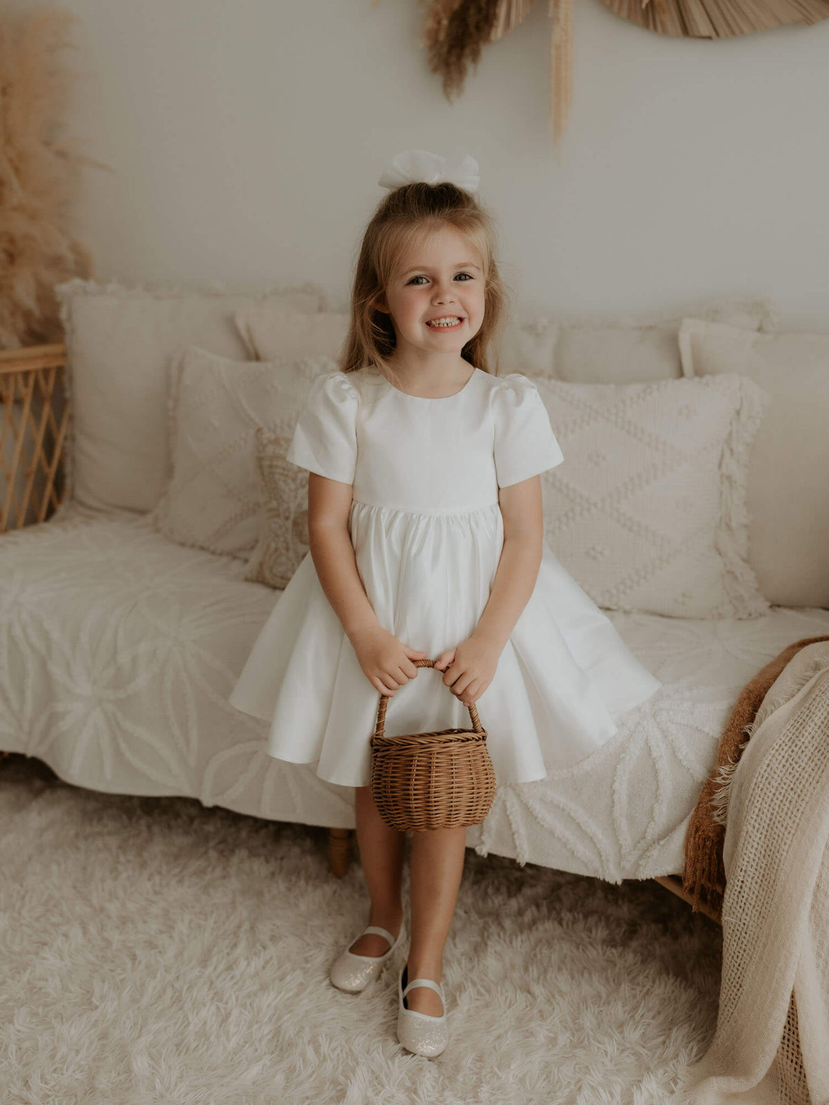 Charlotte satin flower girl dress is worn by a young girl.