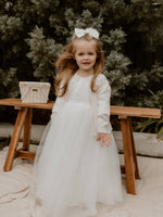 A young girl stands wearing a flower girl dress and our Chloe flower girl cardigan.