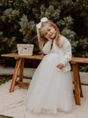 Chloe flower girl cardigan is worn by a young girl, she also wears a tulle flower girl dress and satin bow clip in her hair.