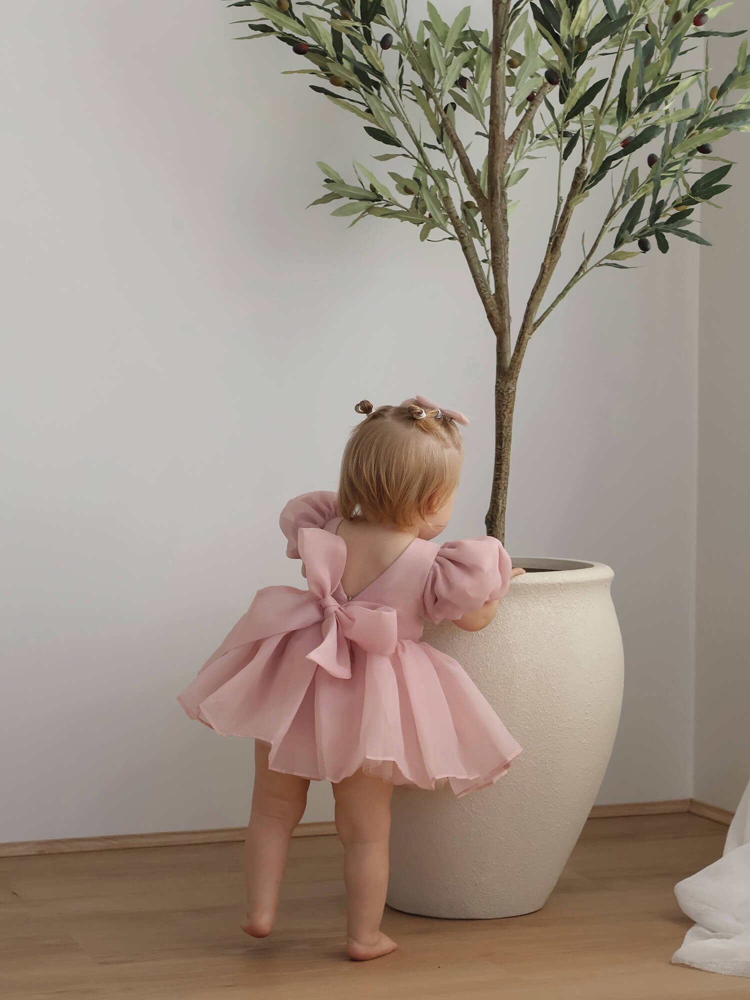 Cleo blush puff sleeve flower girl romper from the back showing the oversized bow at the back.