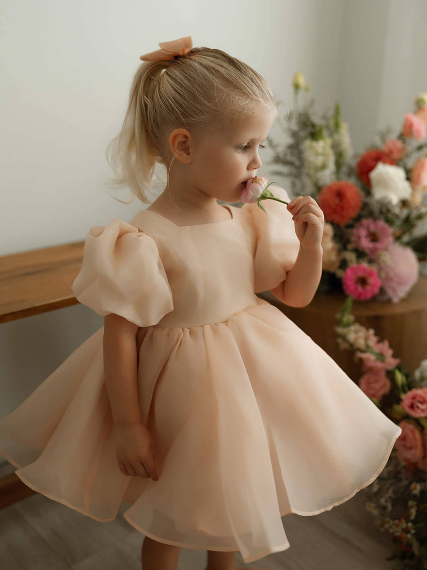 Champagne organza flower girl dress is worn by a toddler.