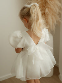 Toddler flower girl dress, our Cleo romper in ivory organza, is worn by a young girl.