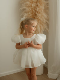 A little girl wears our Cleo baby flower girl romper in ivory organza.