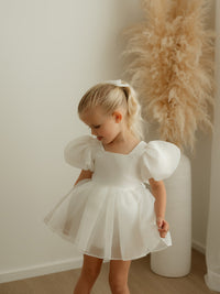 Cleo ivory organza baby flower girl dress is worn by a young girl.
