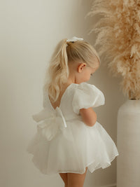 Cleo ivory organza baby flower girl dress is worn by a young girl, showing the organza bow at the back.