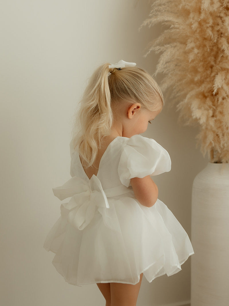 Cleo ivory organza baby flower girl dress is worn by a young girl, showing the organza bow at the back.