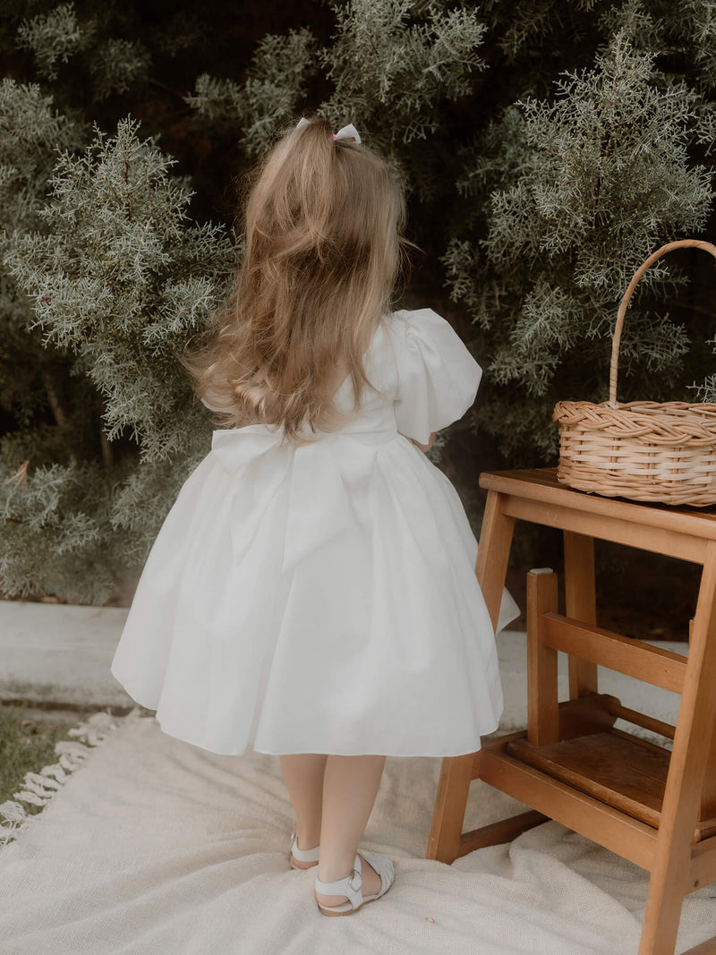 The back of our Cleo linen puff sleeve flower girl dress, showing the linen bow at the back.