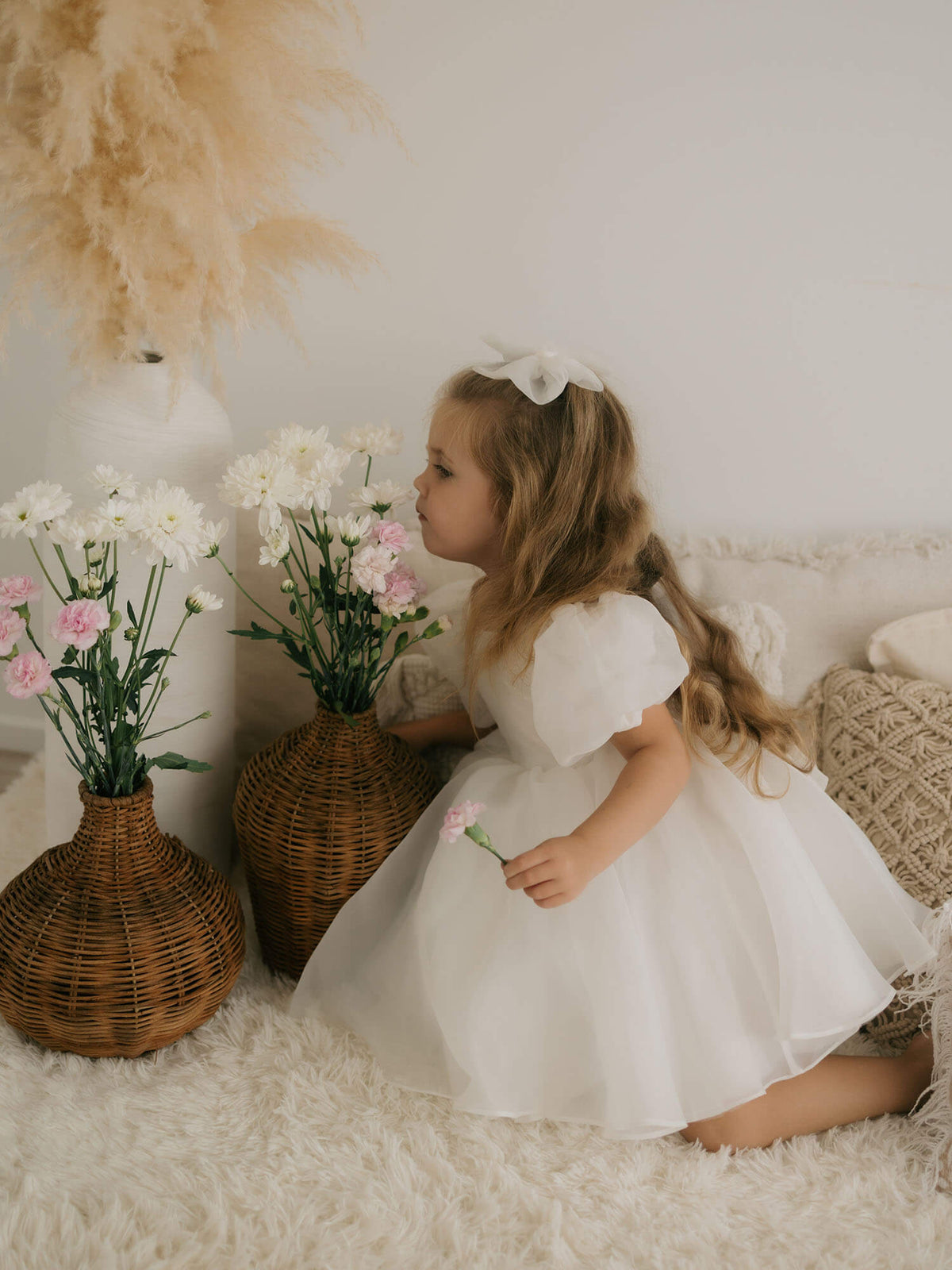 Cleo flower girl dress and medium tulle bow in ivory are worn by a young girl.