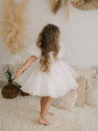 A young girl twirls wearing our Cleo organza flower girl dress.
