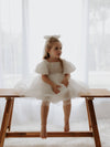 Cleo organza puff sleeve flower girl dress in ivory is worn by a young girl along with a tulle bow hair clip.