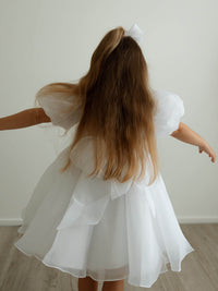 A young girl spins wearing our Cleo flower girl dress in pure white.