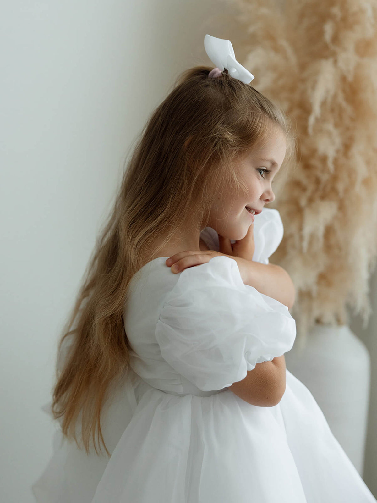 Cleo pure white puff sleeve flower girl dress is worn by a young girl.