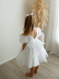 Cleo pure white flower girl dress is worn by a young girl, showing the oversized bow at the back.