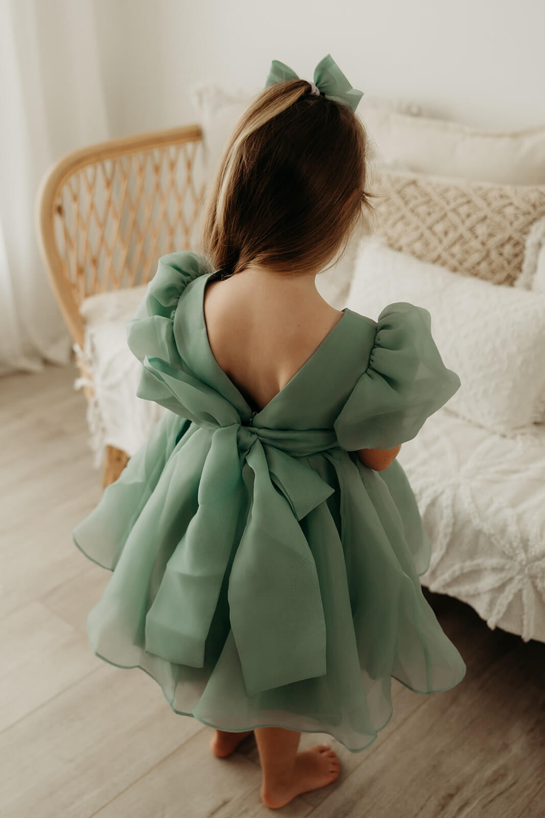 Cleo Jade green flower girl dress is shown from the back on a young girl. Showing the oversized back bow on this green organza dress.