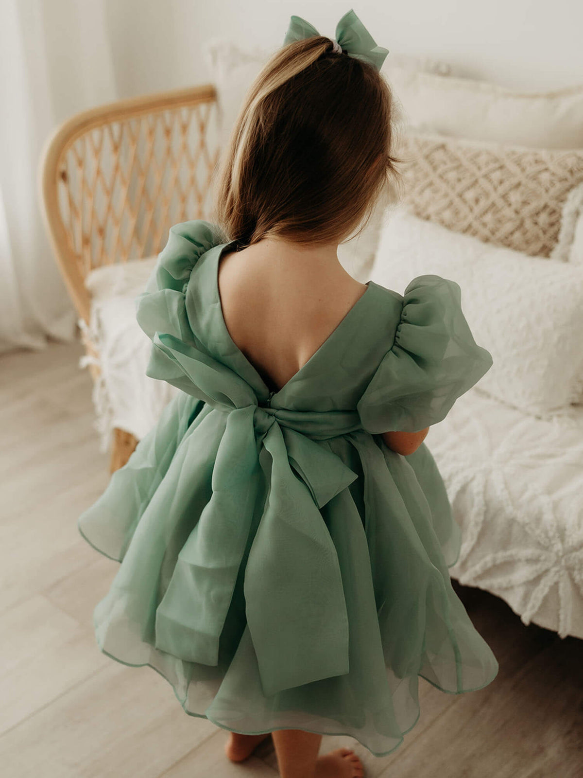 Cleo Jade green flower girl dress is shown from the back on a young girl. Showing the oversized back bow on this green organza dress.