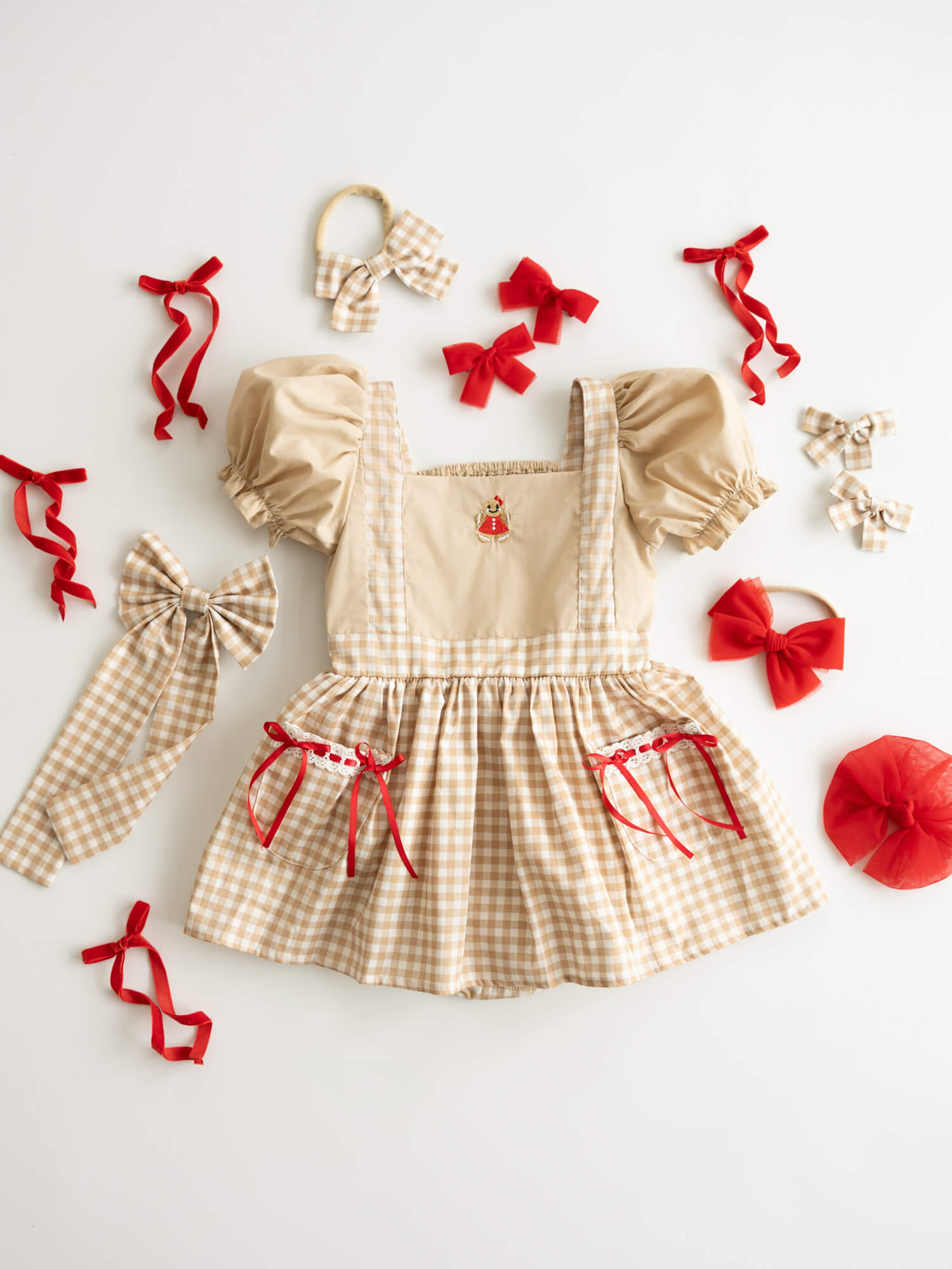 Ellie Christmas baby romper in Gingerbread plaid, with Gingerbread man embroidery and red bow accents.