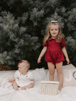 Sisters wear matching Emma Christmas rompers in ivory & crimson.