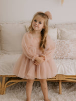 Eva champagne flower girl dress is worn by a girl, along with a matching flower girl bow.