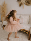 A young girl twirls wearing our Eva champagne flower girl dress and matching tulle hair bow.