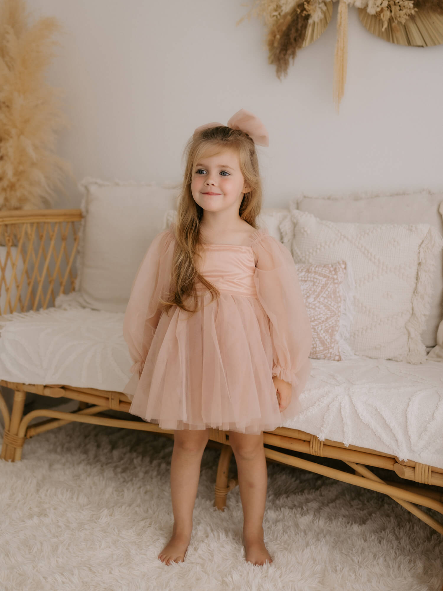 Eva champagne tulle sleeve flower girl dress is worn by a flower girl.