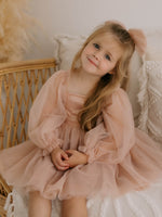 Champagne Eva flower girl dress is worn by a young flower girl, she also wears a tulle bow in her hair.