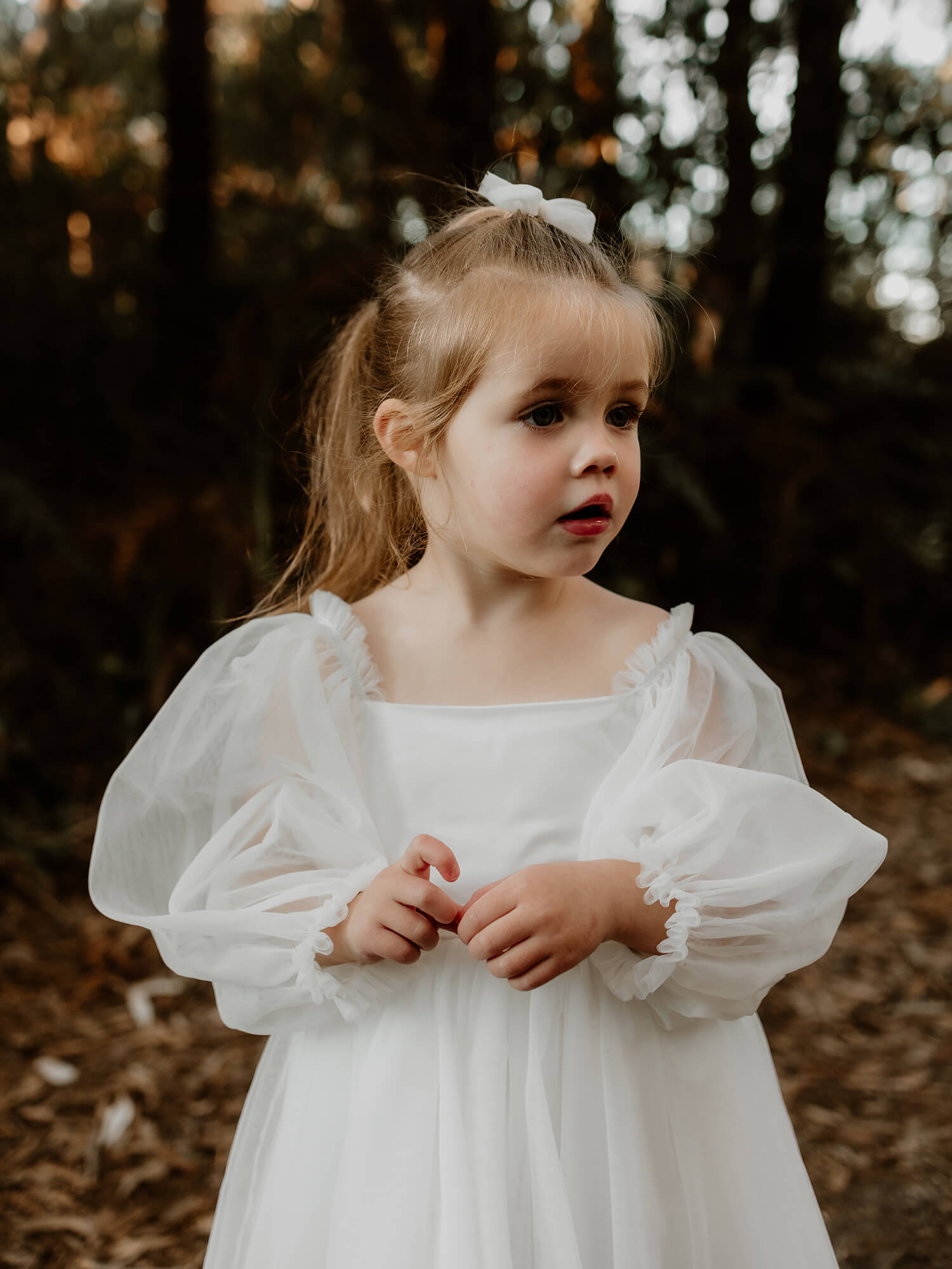 Eva flower girl dress with sating bodice and full length sleeves shown close up on a young flower girl.