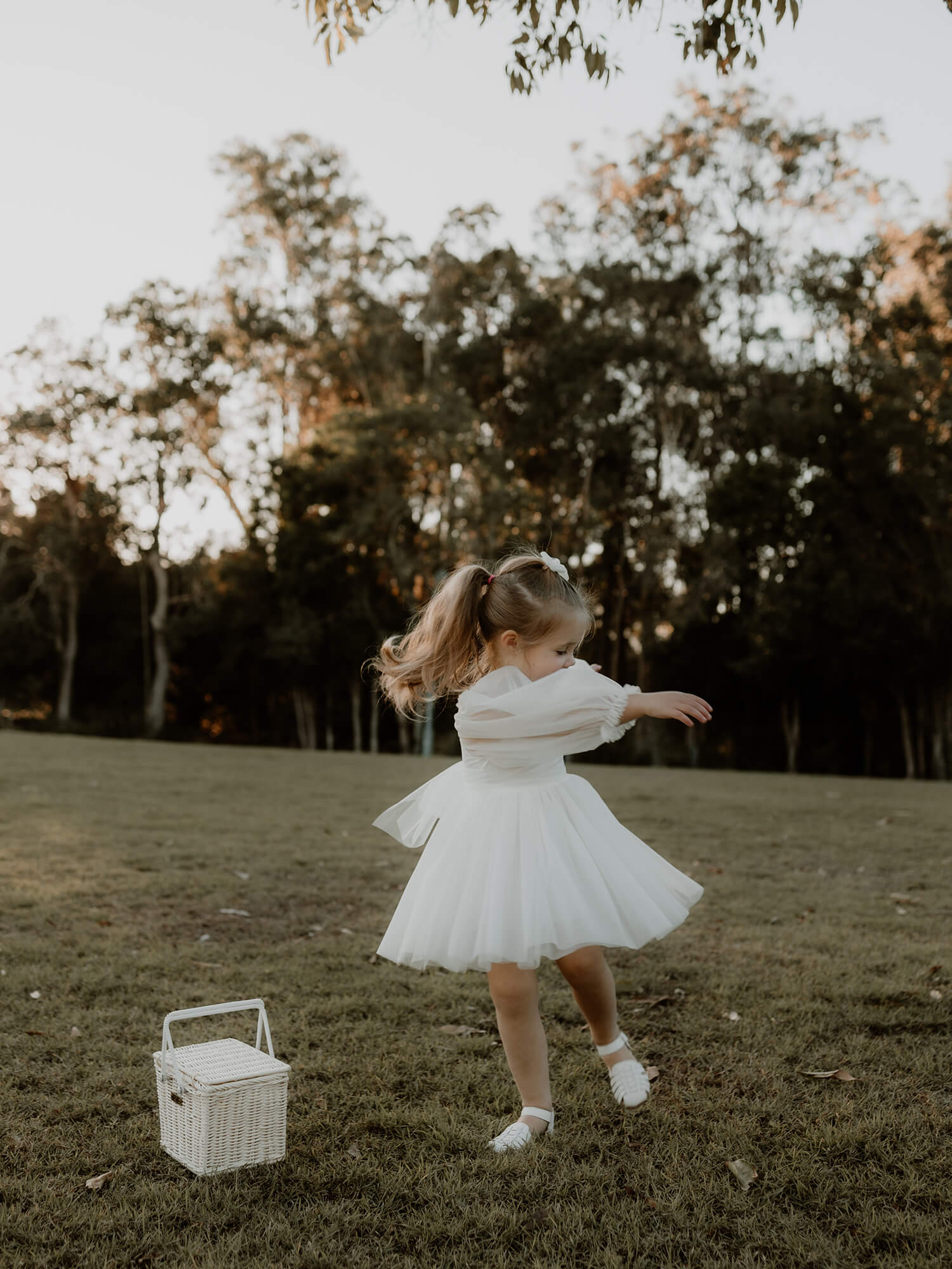 Twirling flower girl wears our Eva tulle sleeve flower girl dress in ivory.
