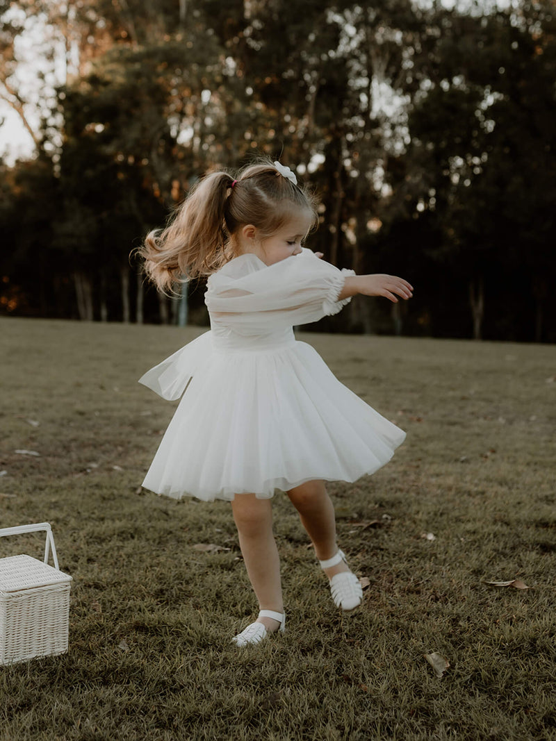 Eva tulle sleeve flower girl dress is worn by a young girl who is twirling.