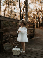 Eva ivory tulle flower girl dress is worn by a young girl, showing the full length tulle sleeves and tea length tulle skirt.