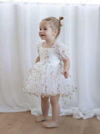 Fleur meadow flower girl romper dress is worn by a toddler.