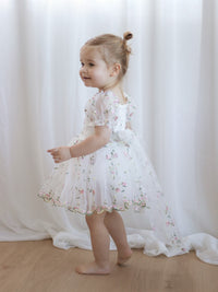 Fleur meadow pink flower girl romper is worn by a toddler, showing the organza bow at the back.