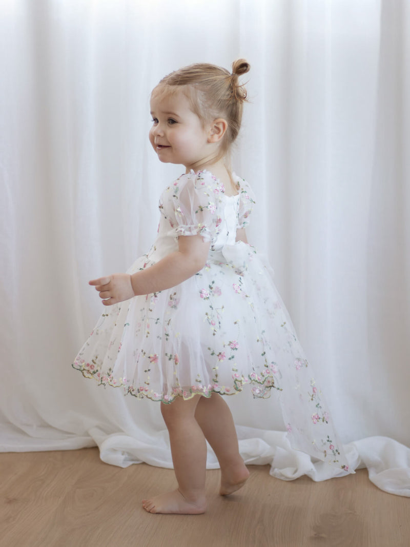 Fleur meadow pink flower girl romper is worn by a toddler, showing the organza bow at the back.