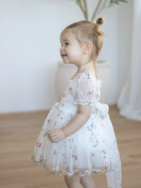 A toddler wears our pink floral organza Fleur romper.