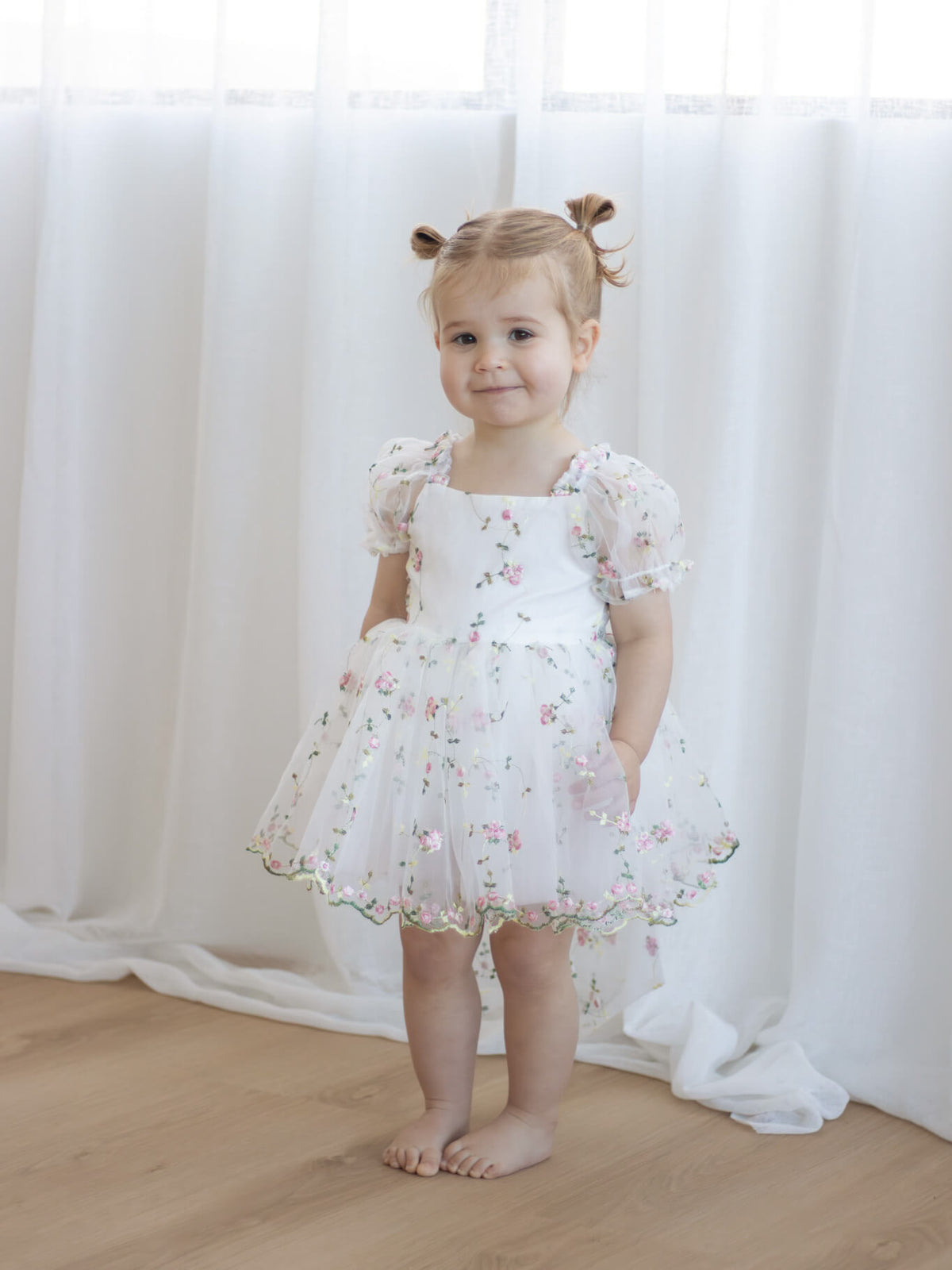 A young girl wears our Fleur pink floral flower girl romper for babies and toddlers.