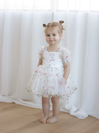 A young girl wears our Fleur pink floral flower girl romper for babies and toddlers.