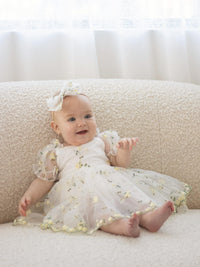 A little baby wears our Fleur lemon yellow floral baby romper.