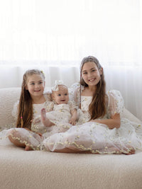 Sisters sit wearing matching Fleur lemon blossom flower girl outfits.