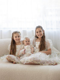 Sisters sit together wearing matching Fleur lemon blossom, yellow floral flower girl dresses.