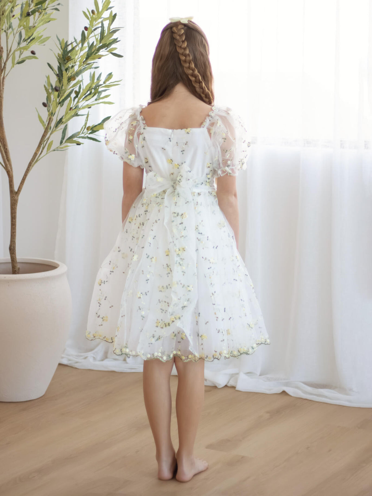 The back of our lemon yellow floral embroidered girls dress, the Fleur dress in lemon blossom.