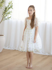 A girl wears our Fleur flower girl dress in lemon blossom.
