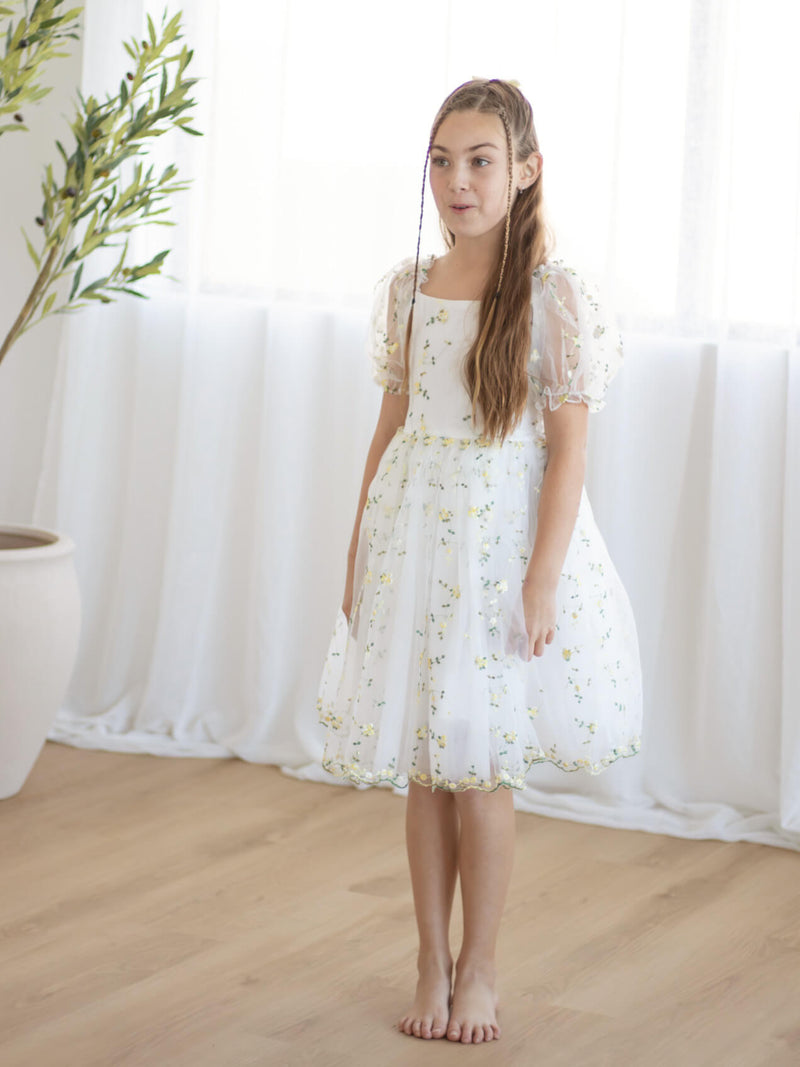 A girl wears our Fleur flower girl dress in lemon blossom.