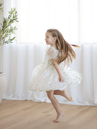 A young girl dances wearing our Fleur flower girl dress in lemon blossom.