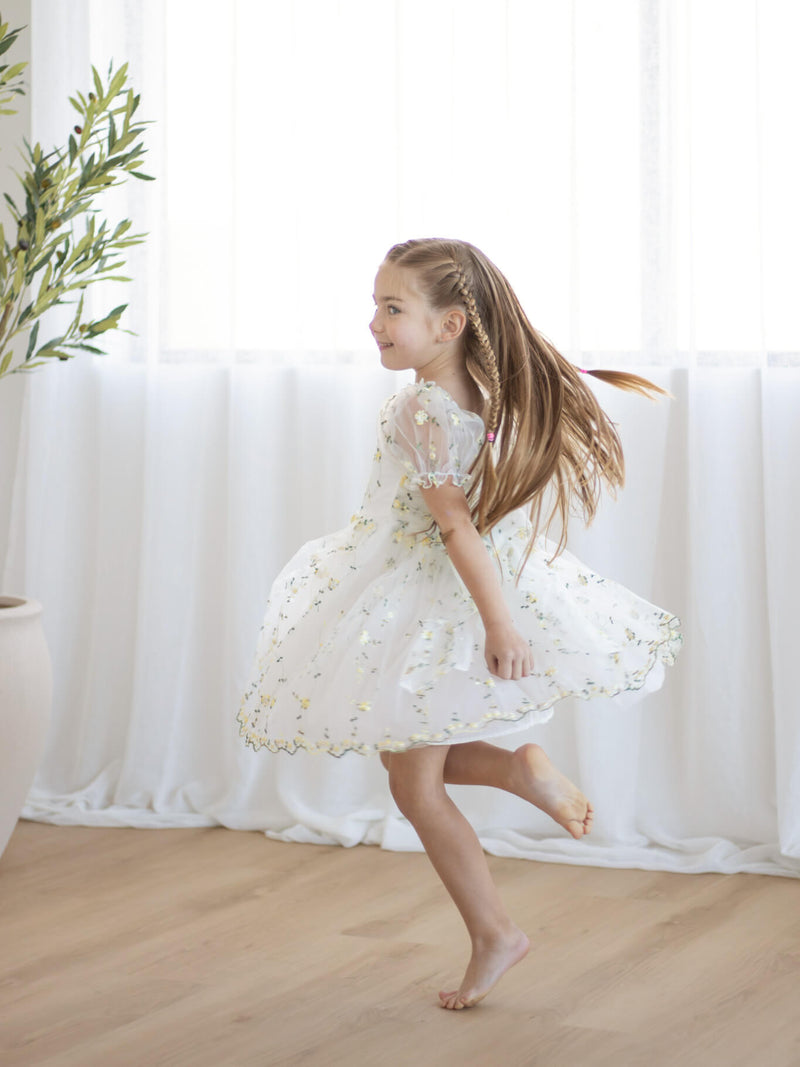 A young girl dances wearing our Fleur flower girl dress in lemon blossom.