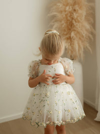 Fleur lemon blossom baby flower girl romper is worn by a young girl.