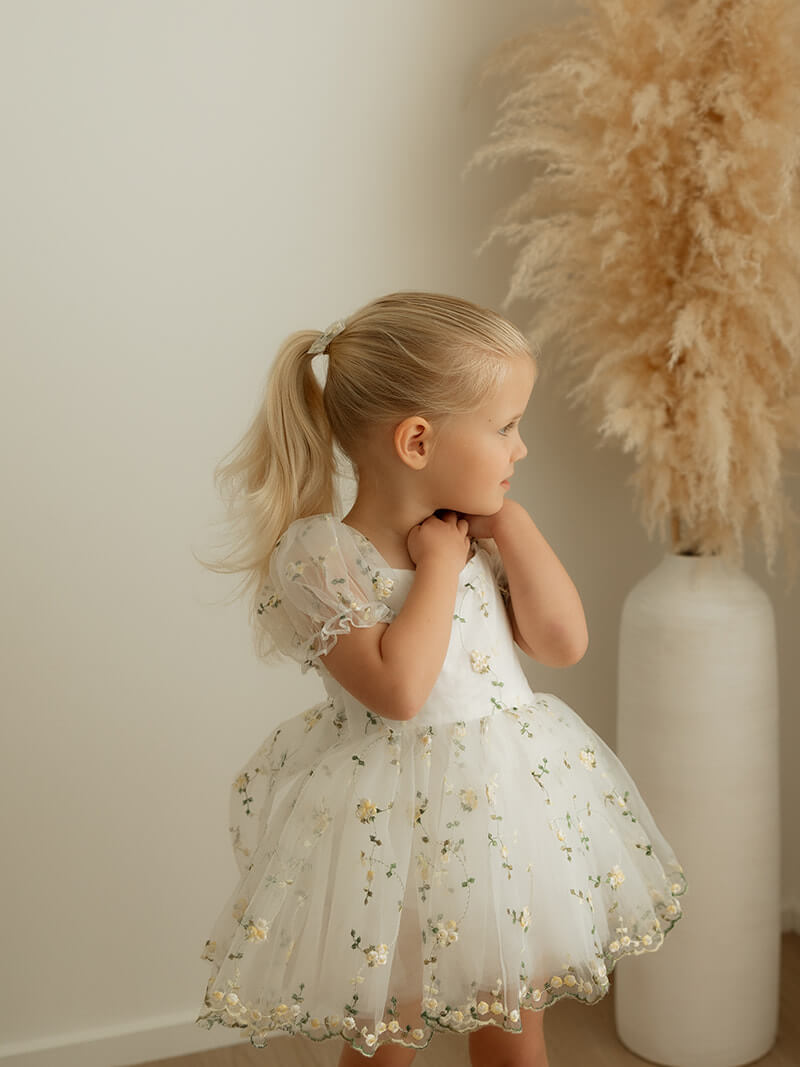 A young girl wears our Fleur lemon floral flower girl romper.