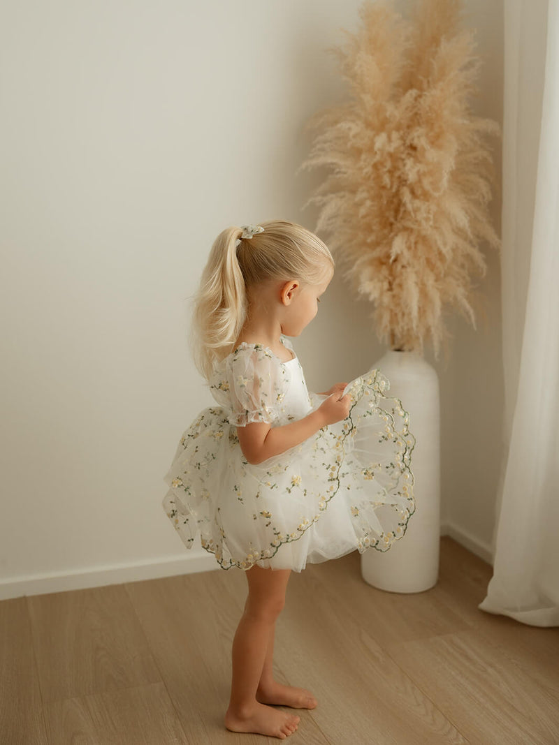 A little girl dances wearing our Fleur lemon yellow floral organza baby romper.